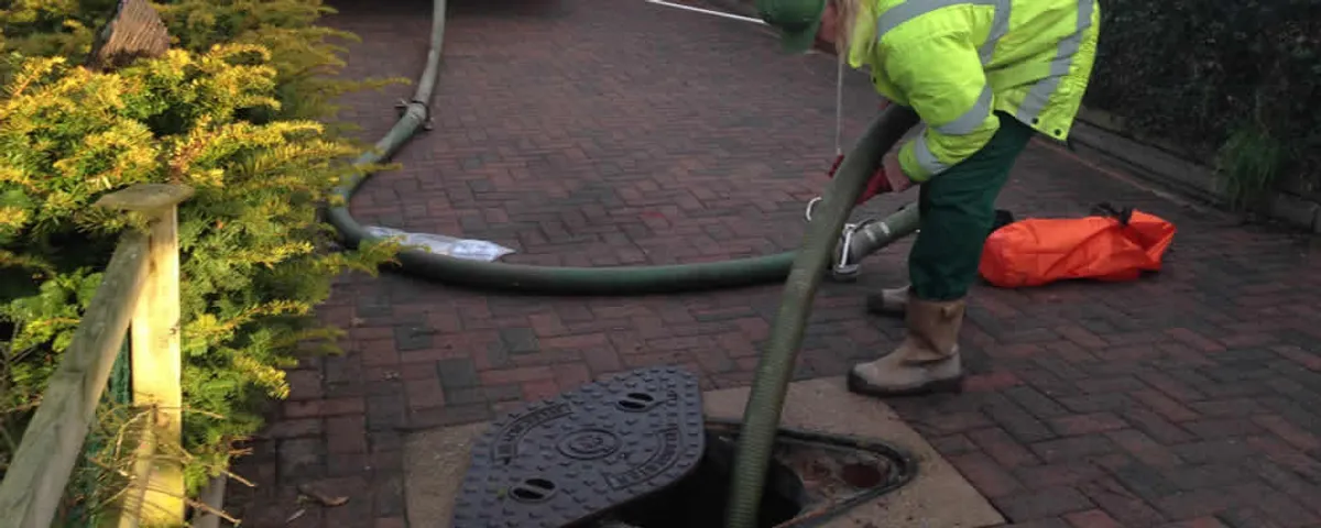 Septic tank cleaning technician servicing a septic tank with a vacuum hose in Charleston, SC