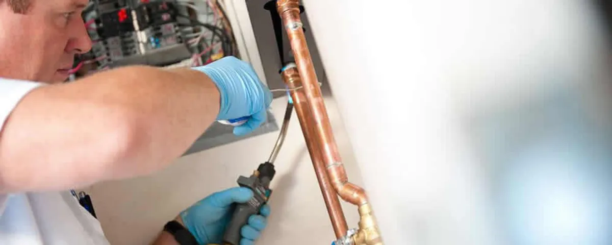 Water heater repair technician testing copper pipe connections and controls in Charleston, SC